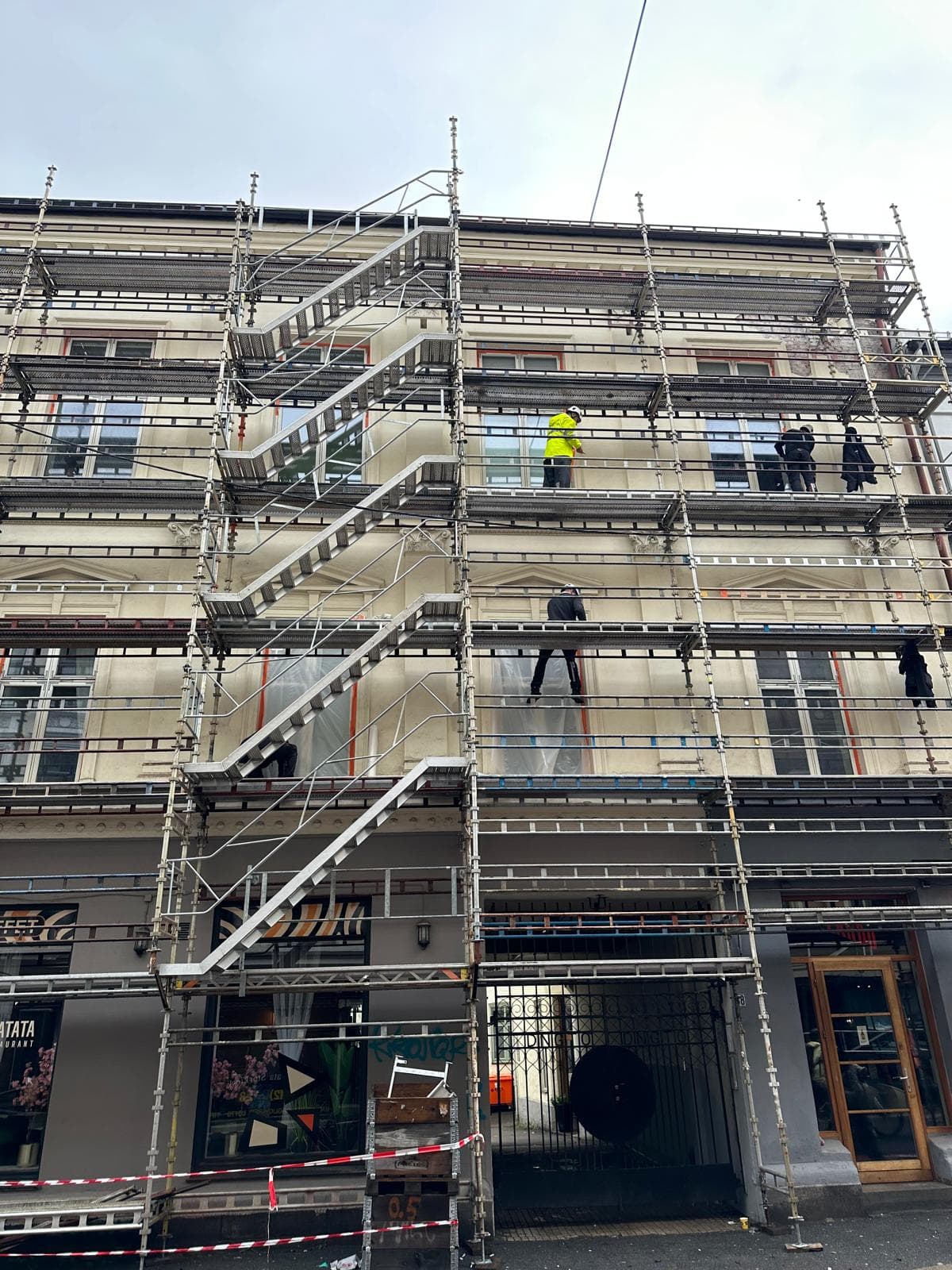 Stillas foran en bygårdsfasade under rehabilitering.